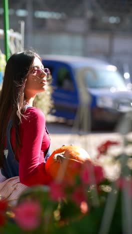 mujer sosteniendo una calabaza en un jardín