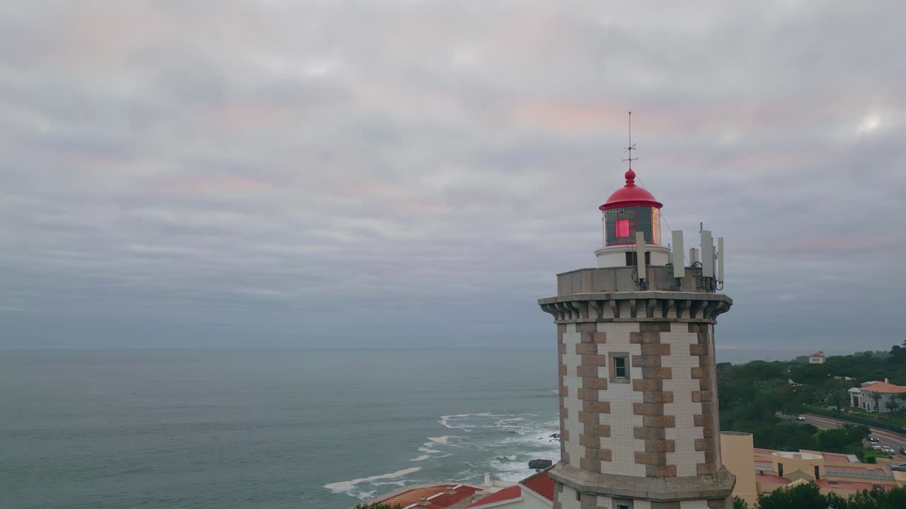Dramatic sky coastal lighthouse drone shot. Deep ocean washing rough coastline