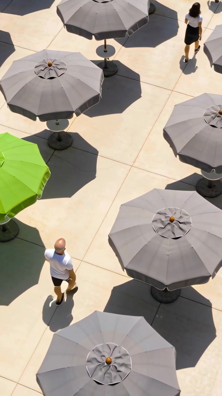 Video verticale: Una signora con top bianco e gonna scura cammina da un punto basso verso la piscina, mentre un uomo entra all'ombra verde.