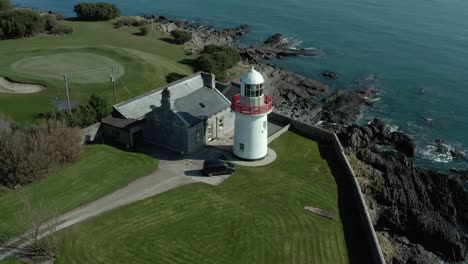 aerial spinning shot of lighthouse near low tide ocean on sunny day