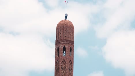 pan up for the scale of the minaret silo while a worker on the top trying to finish it