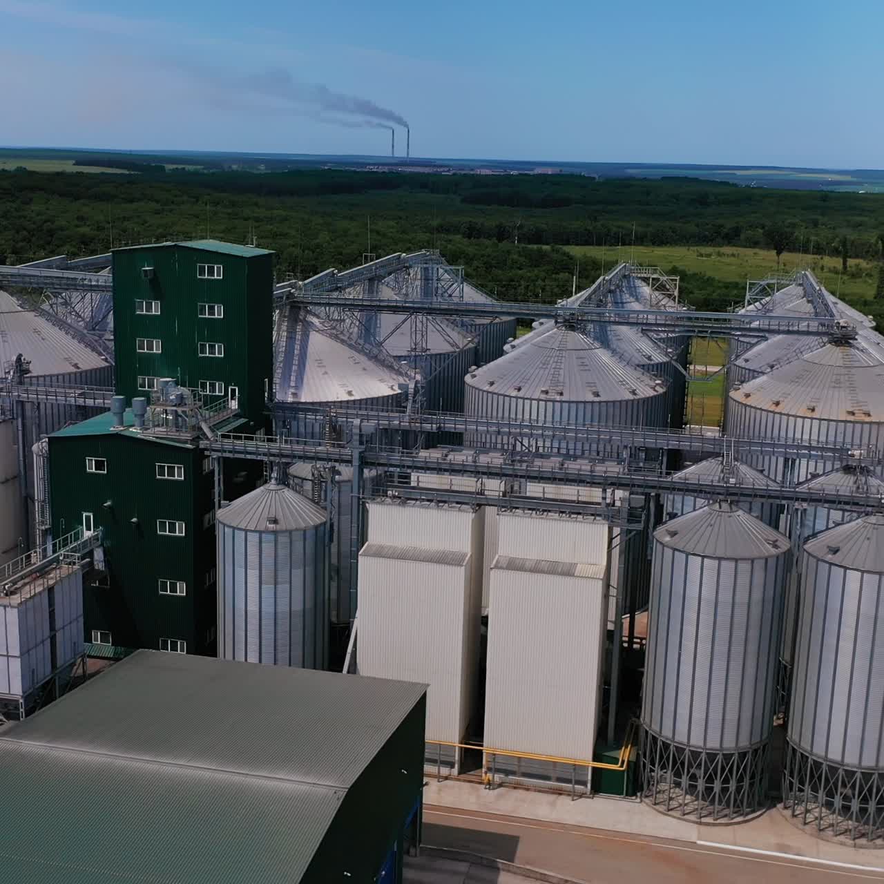 Exterior of the huge silo tanks at the agricultural plant. Steel tanks of the granary complex against the nature background