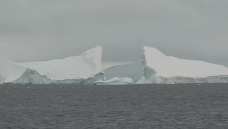 big ice berg in distance break in two parts, very dangerous