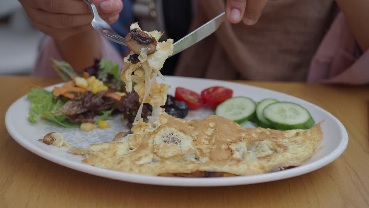 People eating a healthy breakfast with omelette, salad and cucumber