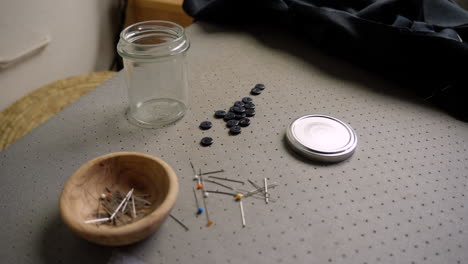 Pot of pins with needle and buttons in seamstress&#039;s fashion studio
