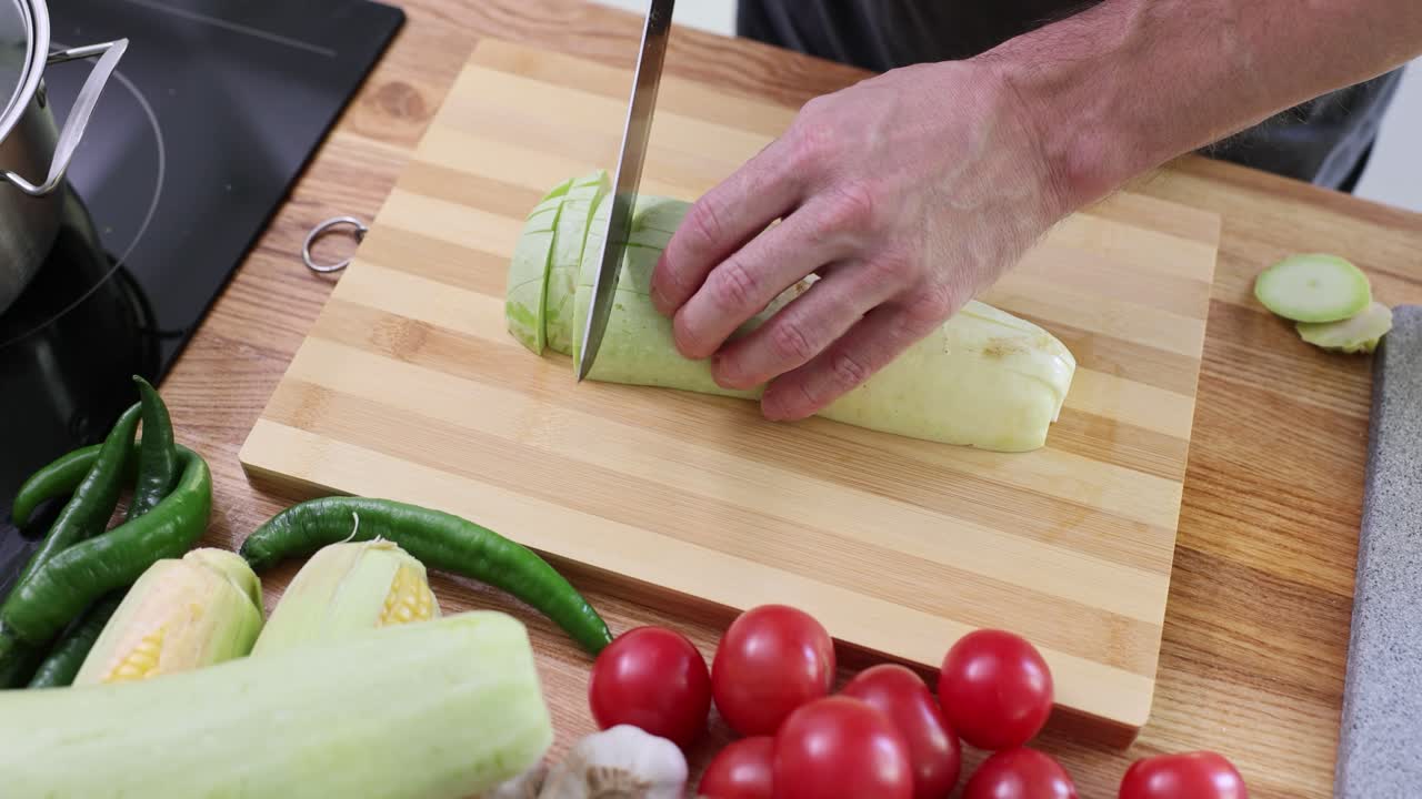 Mani che tagliano le zucchine a cubetti durante una rapida preparazione di pasti casalinghi.