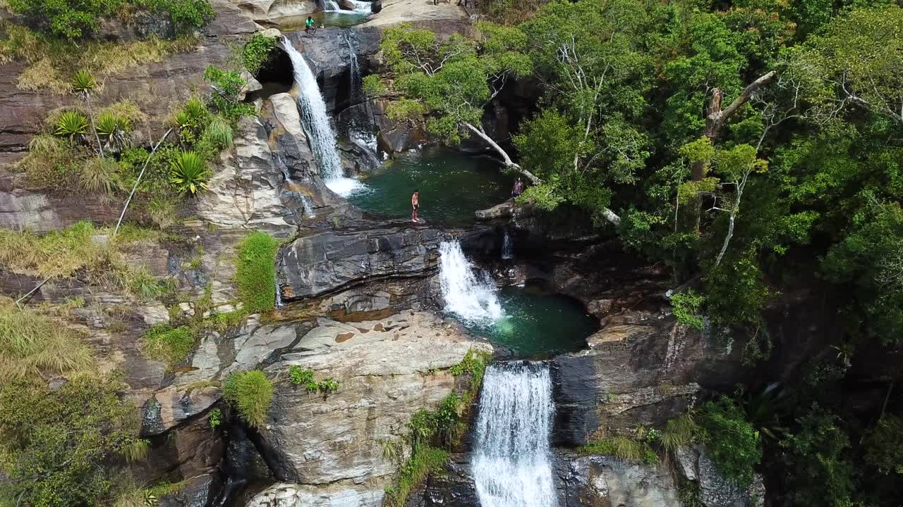 turistas que saltan del acantilado en la cascada de las cataratas de diyaluma en sri lanka, vista aérea