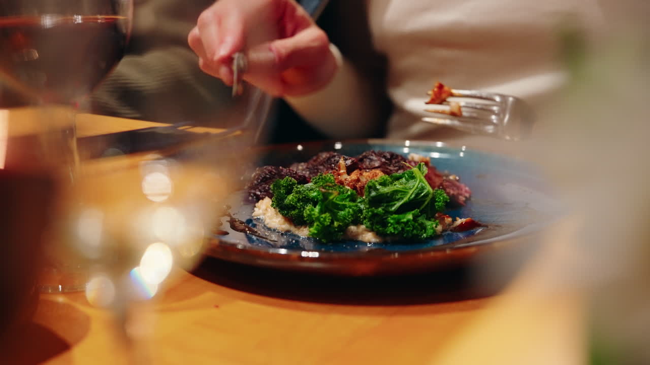 Close up shot of meat course with vegetables being cut with cutlery at the restaurant. Culinary experience. Vibrant healthy food.