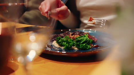 close up shot of meat course with vegetables being cut with cutlery at the restaurant. culinary experience. vibrant healthy food.