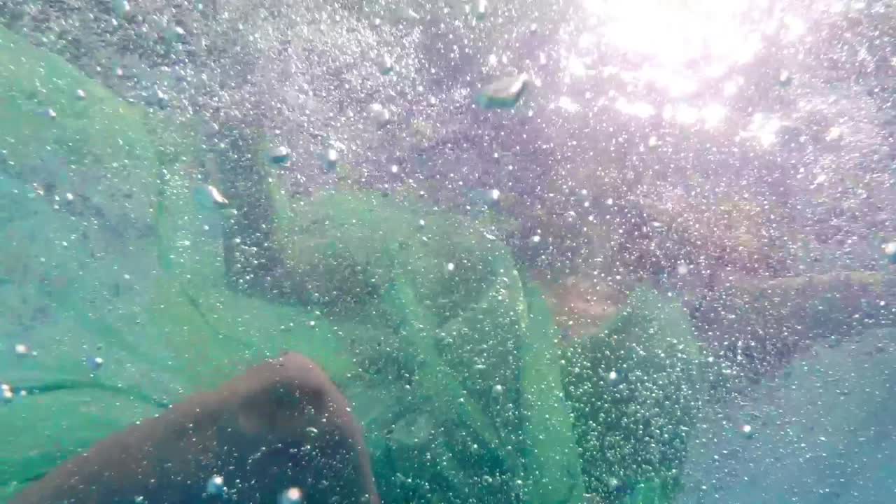 푸른 드레스를 입은 아름다운 여성이 수영장에서 다이빙하고 있습니다.