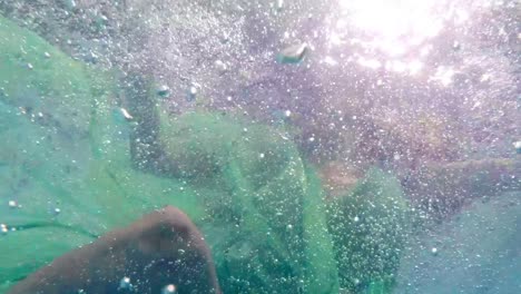 hermosa mujer con vestido verde buceando en la piscina
