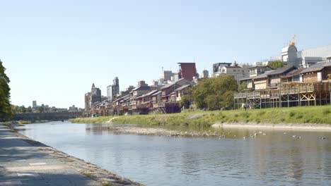 Houses-alongside-a-beautiful-river-on-a-hot-summer-day-in-Kyoto,-Japan-soft-lighting-slow-motion-4K