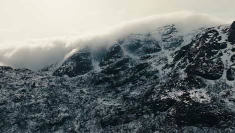 thick clouds over snow mountains in lofoten, norway. aerial shot