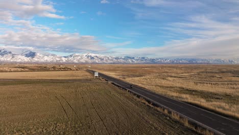 Toma-Aérea-Conduciendo-Una-Motocicleta-Por-Una-Carretera-Distante-Con-Una-Vista-Increíble-En-Syracuse,-Utah