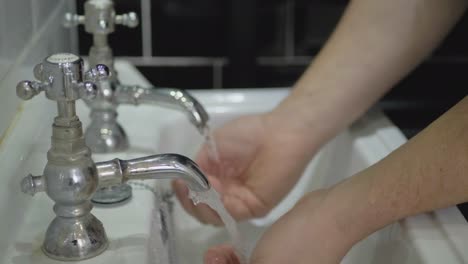 man washes hands in sink with two separate hot and cold water taps