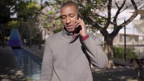 Man-talking-by-cell-phone-and-smiling-on-street