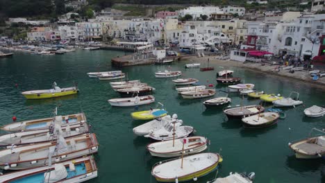 Aerial-dolly-over-fishing-and-speed-boats-anchored-in-rows-at-capri-island,-Italy