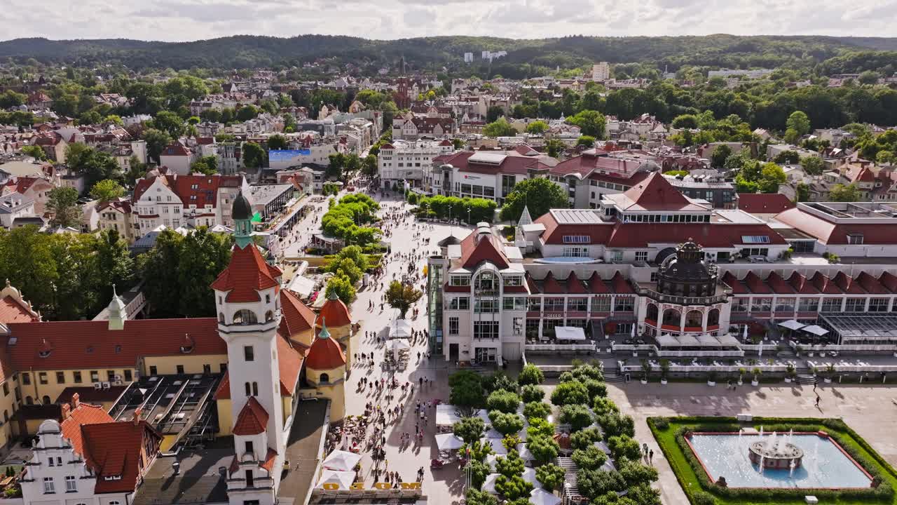 Scenic aerial shot shows Sopot city center with tourists and green hills beyond