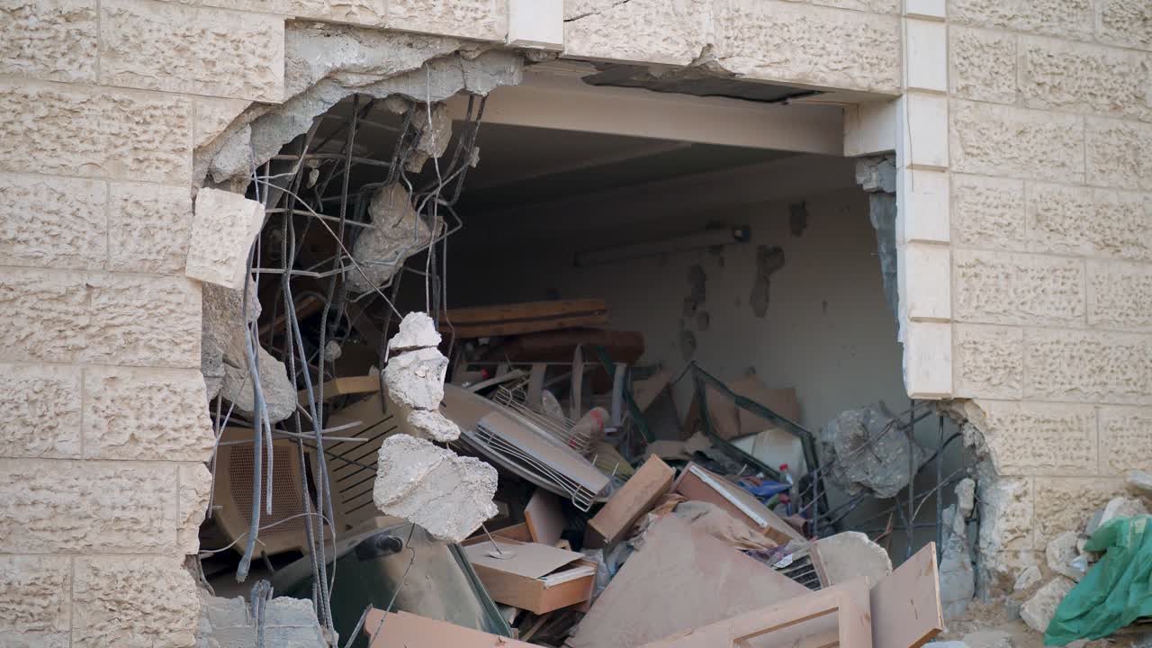 Static ground view of a single bombed building in Gaza with a gaping hole and exposed structure.