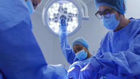 asian surgeon wearing surgical cap and face mask operating in hospital