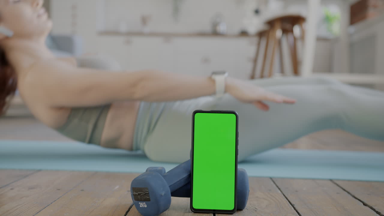 Woman doing workout at home with smartphone and dumbbells