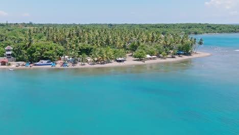 Aerial-view-of-beautiful-sandy-beach,-with-turquoise-water-and-tropical-palm-trees-in-summer