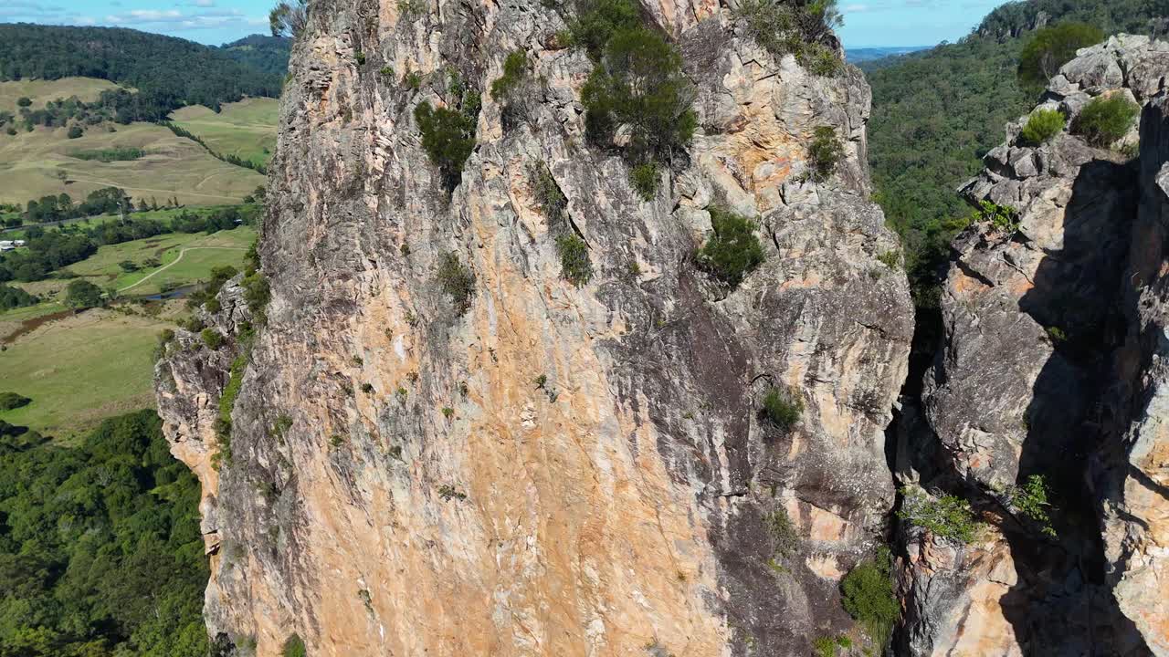 Drone footage captures the rugged rhyolite formations of Nimbin Rocks, surrounded by lush eucalyptus forests under clear skies