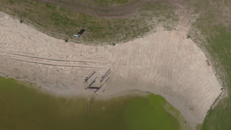 vista desde arriba de un lago recreativo construido en los países bajos que muestra la playa y los campos verdes alrededor del agua verde y exuberante