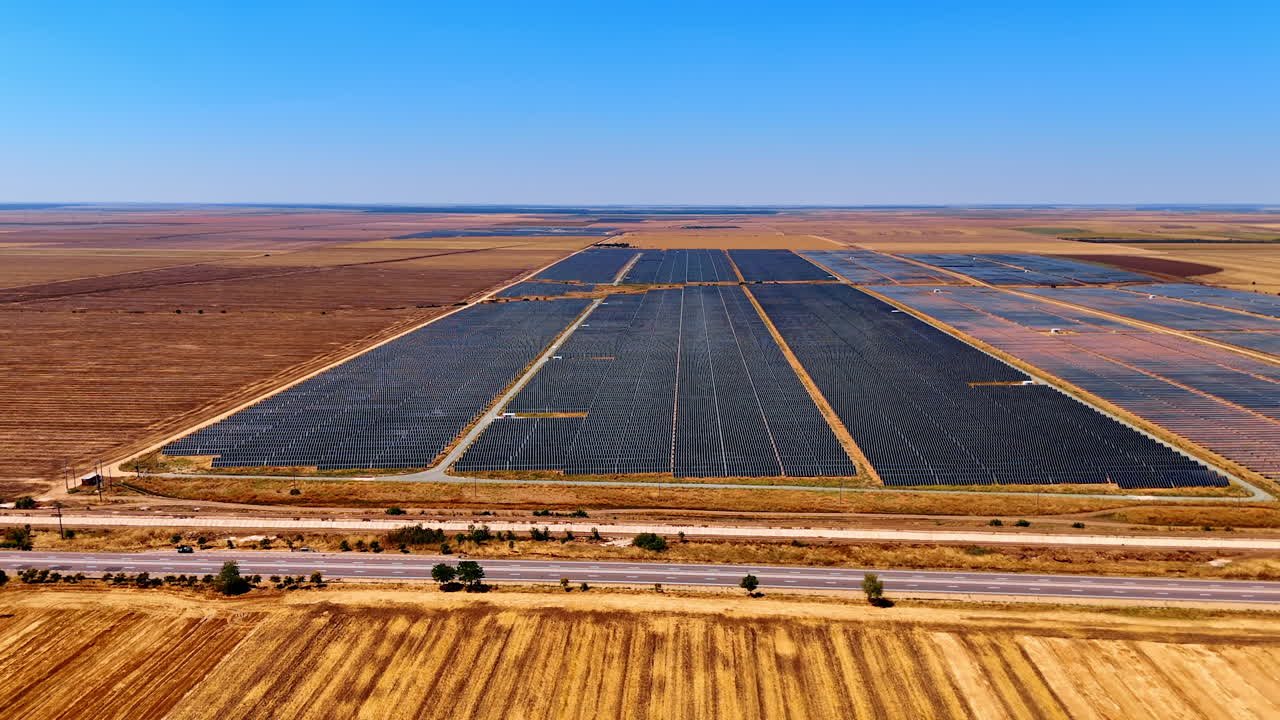 Approaching the site covered with solar panels. Bare fields with no vegetation around. Aerial view