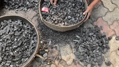 Top-down-shot-of-the-hands-of-a-worker-sorting-trash-from-coal-pieces-before-using-it-in-a-workshop-in-Dhanbad,-Jharkhand,-USA-at-daytime