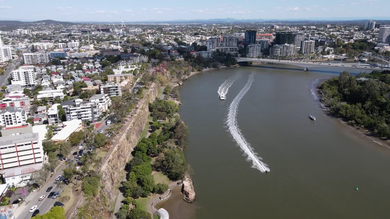 CityCat ferry service traveling along the Brisbane River past the towering Kangaroo Point cliffs. High drone view