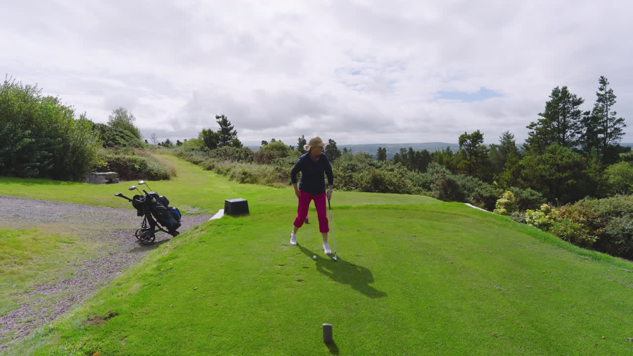 Female golf player playing golf and knocking golf ball out on golf course on cloudy day, copy space