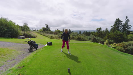 female golf player playing golf and knocking golf ball out on golf course on cloudy day, copy space