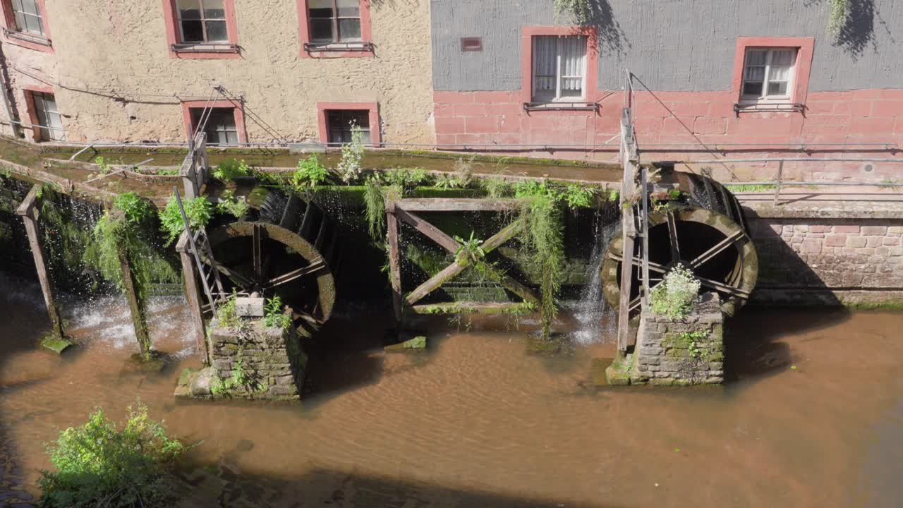 Storiche ruote idrauliche girano accanto a vecchi edifici a Saarburg, Germania.