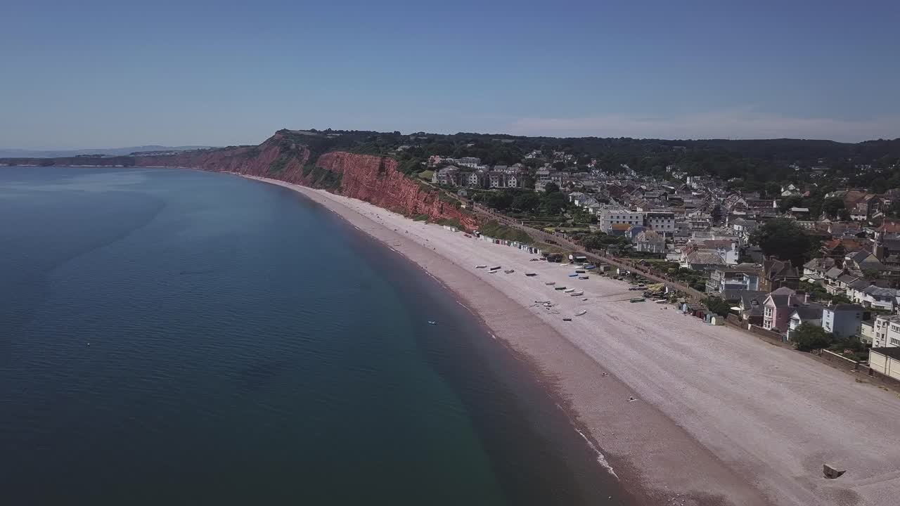 amplia vista aérea de la encantadora ciudad de budleigh salterton, su espaciosa playa de guijarros, sus acantilados triásicos de color rojo oxidado y su mar azul.