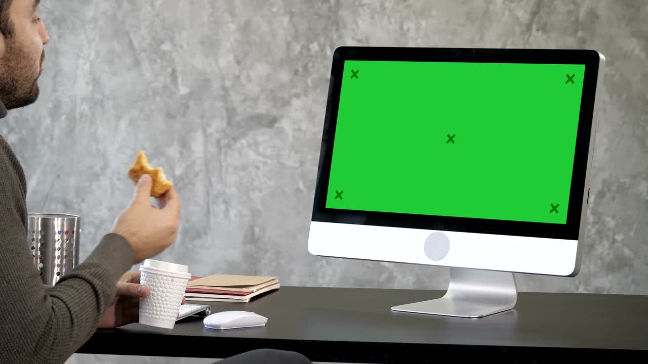 hombre de negocios comiendo comida mientras tiene una llamada por internet. pantalla verde muestra de maqueta