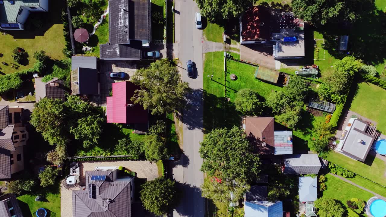 Straight-down drone view of Riga suburb street with car and summer gardens
