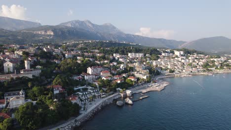 Vista-Aérea-De-La-Pintoresca-Ciudad-Costera-De-Herceg-Novi-Que-Rodea-La-Bahía-De-Kotor-Al-Pie-Del-Monte-Orjen,-Cordillera-De-Montenegro