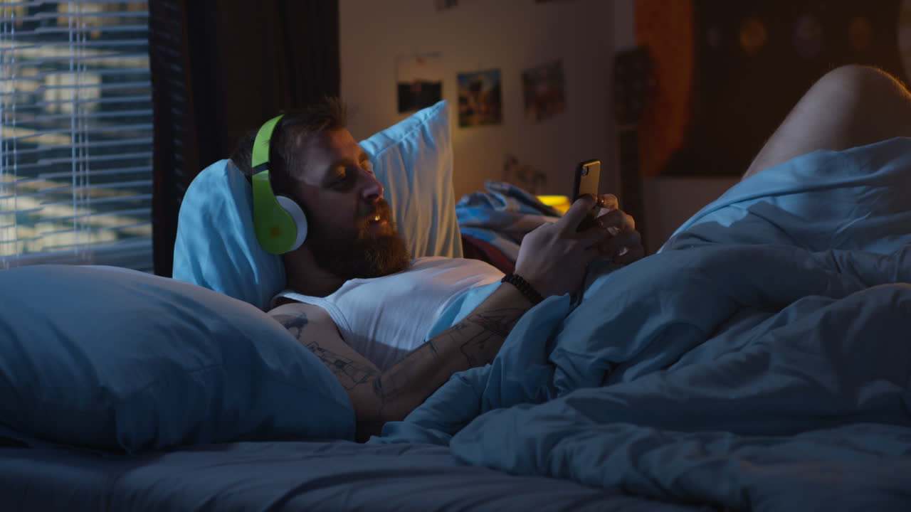 Man in bed listening to music on smartphone