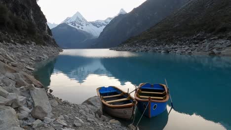 barco amarrado en el lago parón, reflejo de la montaña piramidal en la cordillera andina de aguas tranquilas en el parque nacional huascaran de perú
