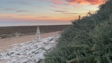 Schwenkansicht-Der-Pyramide-Aus-Weißen-Steinen-An-Einem-Einsamen-Strand-Bei-Sonnenuntergang