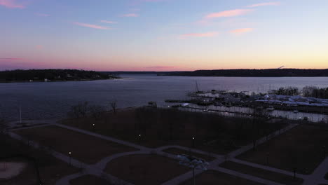 an aerial shot over an empty park focused on the bay during a beautiful sunrise
