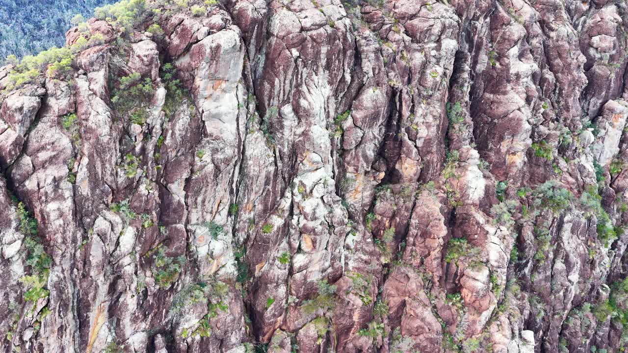 Drone glides over Timor Rock cliffs, revealing sandstone textures and bushland in sunset light