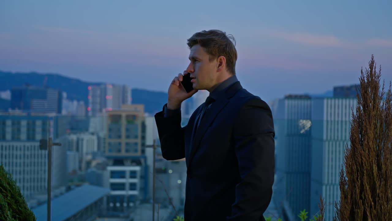 Phone call and talking in city for business, networking and conversation at sunset. Middle age ceo man with smartphone for discussion, communication and speaking to contact on a rooftop at blue hour