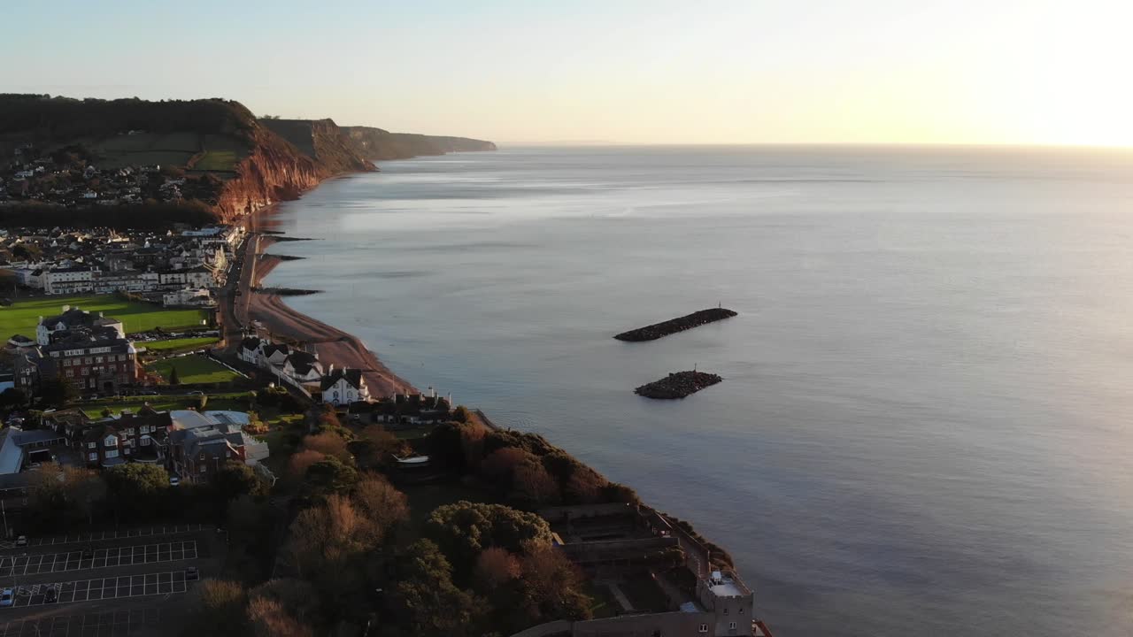 Aerial panning left shot of Sidmouth Devon at sunrise looking out over the beautiful calm sea of Lyme Bay