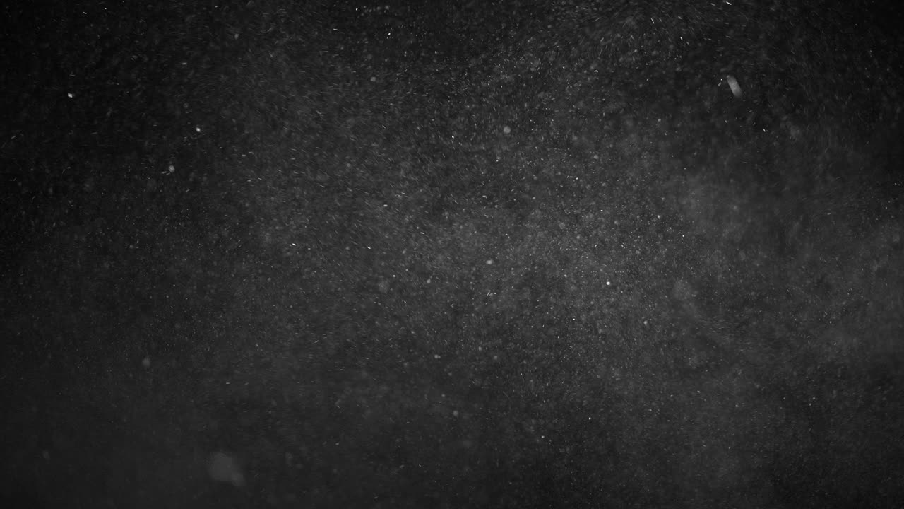 작은 매크로 먼지 입자가 공중에 떠다니며 검은 배경 클로즈업에 떨어집니다.