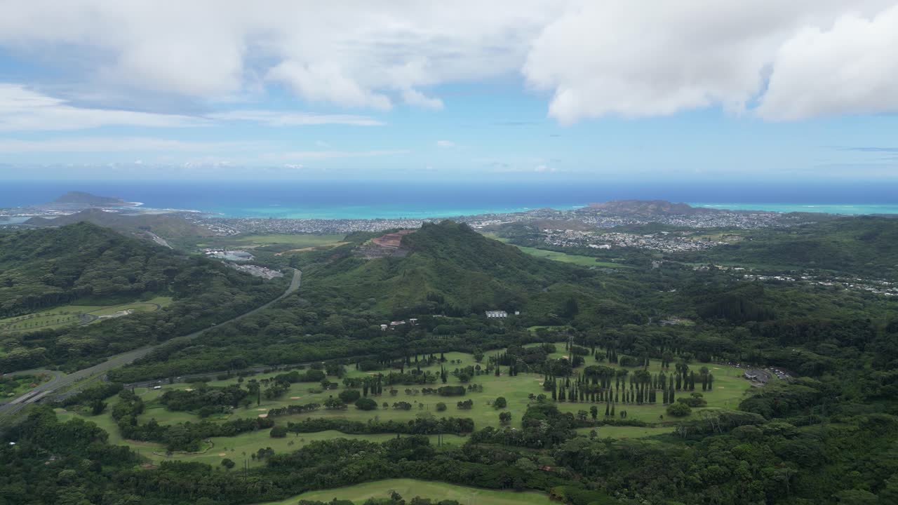 Drone ascends over Big Island, revealing lush terrain, coastline, and urban sprawl.