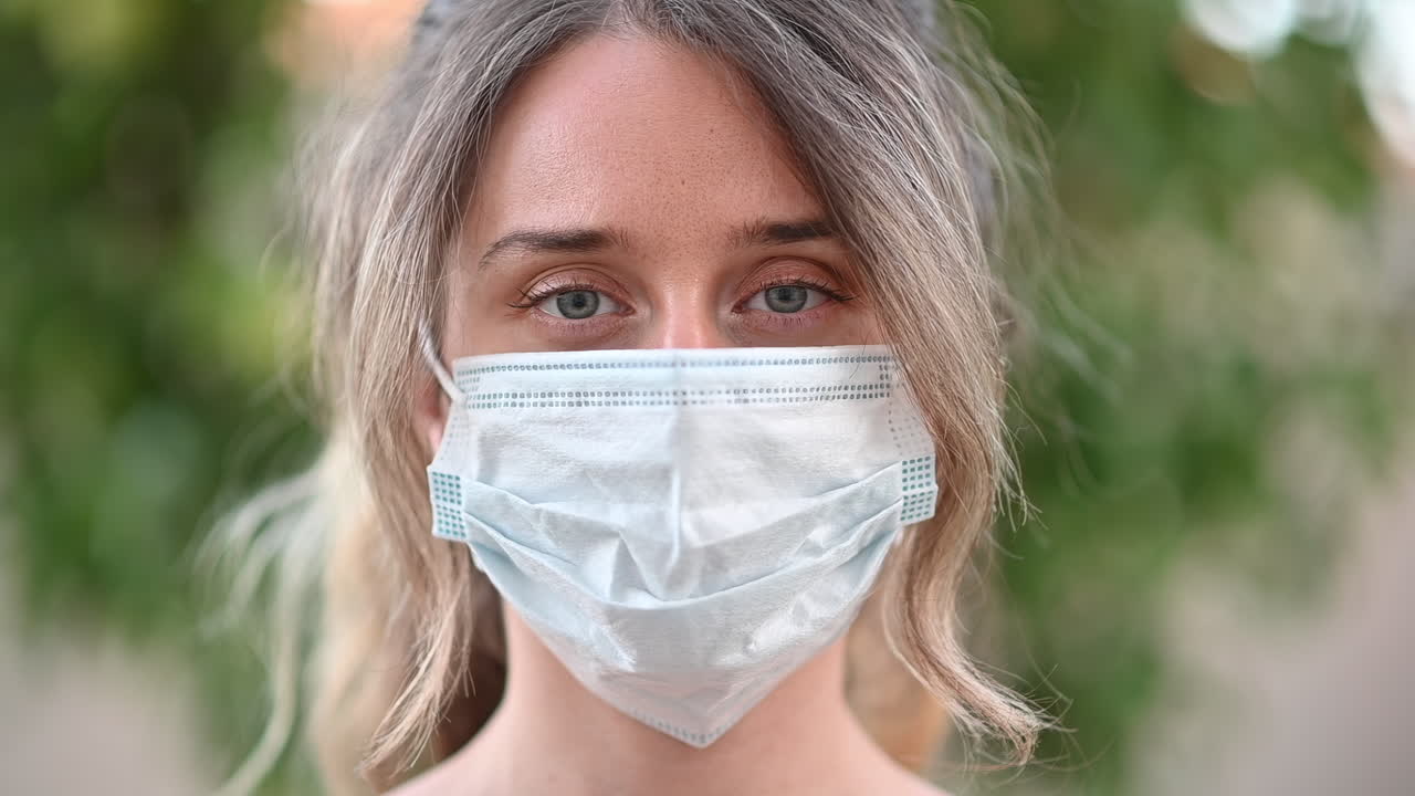 Close up of a young woman wearing a protective medical mask outdoors in soft natural light