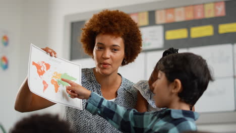 multi-cultural elementary school pupils with female teacher asking question in geography class