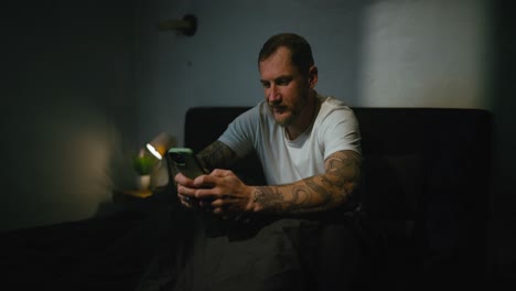 hombre usando el teléfono en la cama por la noche